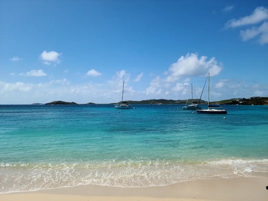 Secret Harbor Beach St. Thomas — calm turquoise water with sailboats and green islands in the background